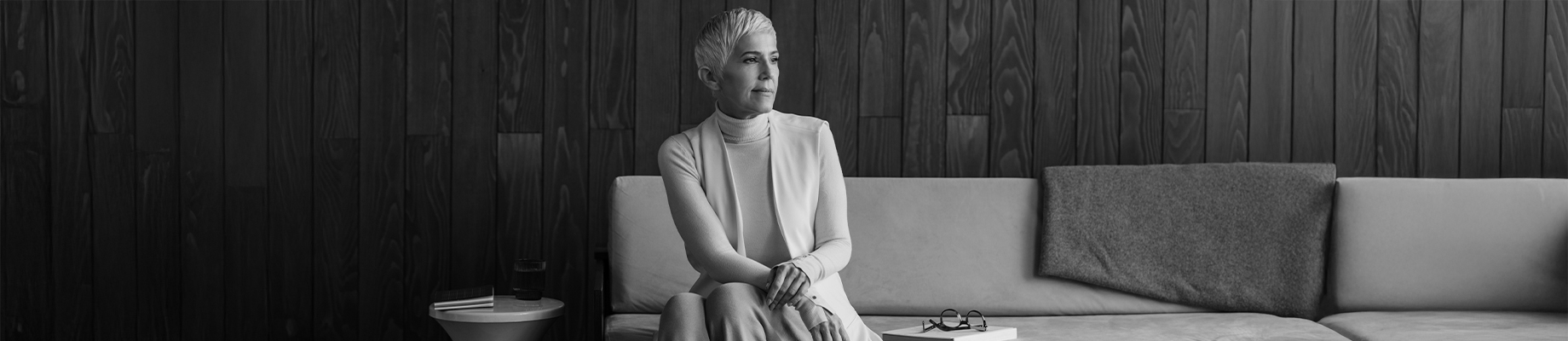 Frau sitzt auf Couch und sinniert, optimistischer Blick